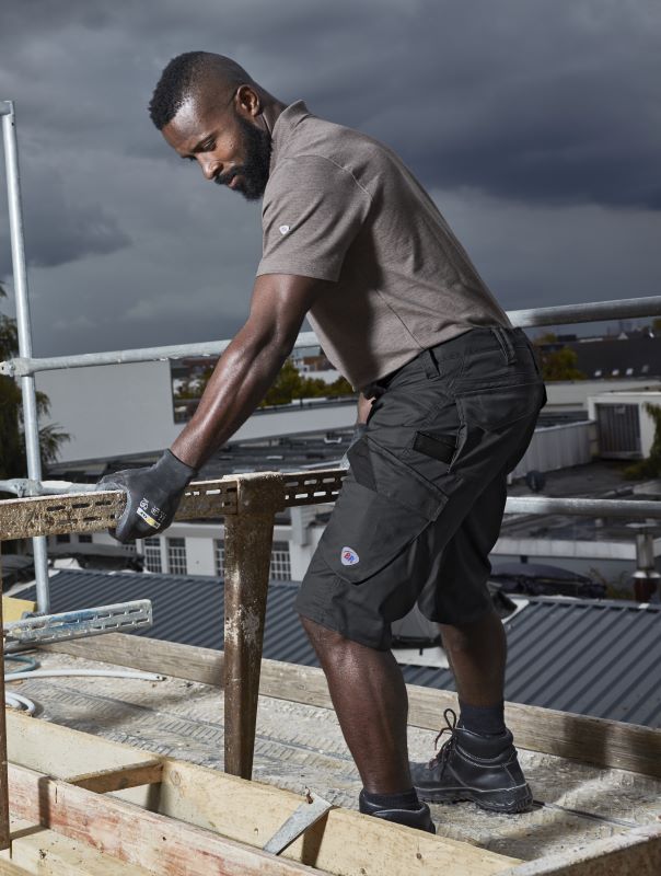 Ein Mann trägt BP® Shorts auf einer Baustelle.